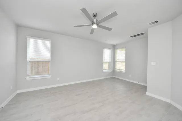an empty room with a window and a ceiling fan