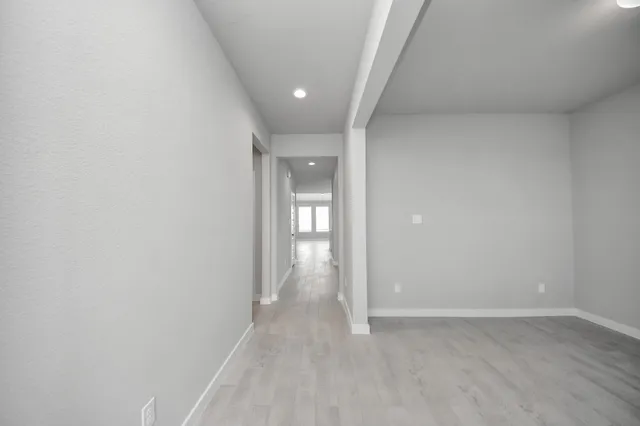 a view of a hallway with wooden floor and a bathroom