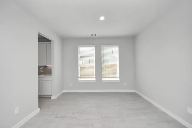 an empty room with a window and a kitchen