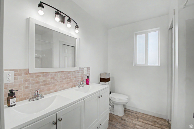 12645 East Cedar Ridge Drive Fairview, UT 84629 - Photo 15 of 34 Bathroom featuring a double vanity with integrated sinks, brick-patterned tile backsplash, a wall-mounted mirror, and a window providing illumination