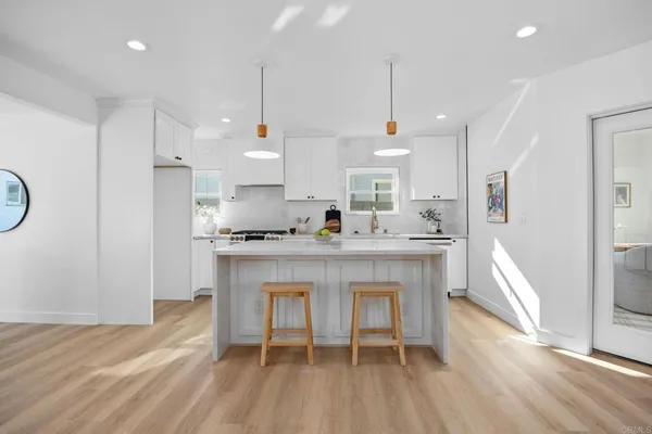 a large kitchen with cabinets wooden floor white stainless steel appliances and view living room