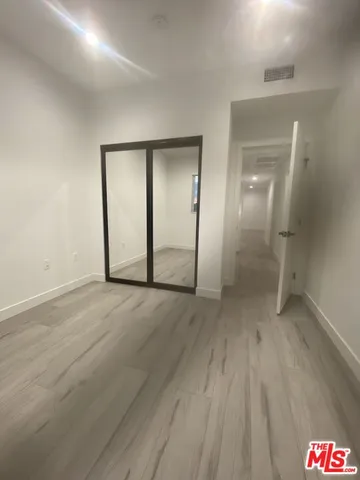 an empty room with wooden floor and mirror