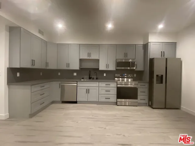 a kitchen with stainless steel appliances granite countertop a refrigerator a stove a sink and white cabinets