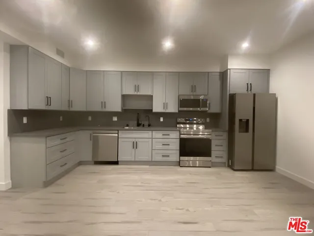 a kitchen with a refrigerator a stove top oven and cabinets