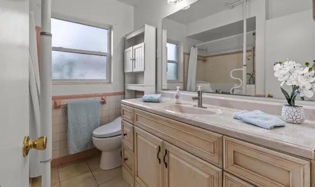 a bathroom with a granite countertop toilet sink and mirror
