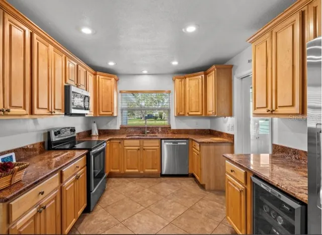 a kitchen with stainless steel appliances granite countertop wooden cabinets a sink dishwasher a stove and a refrigerator