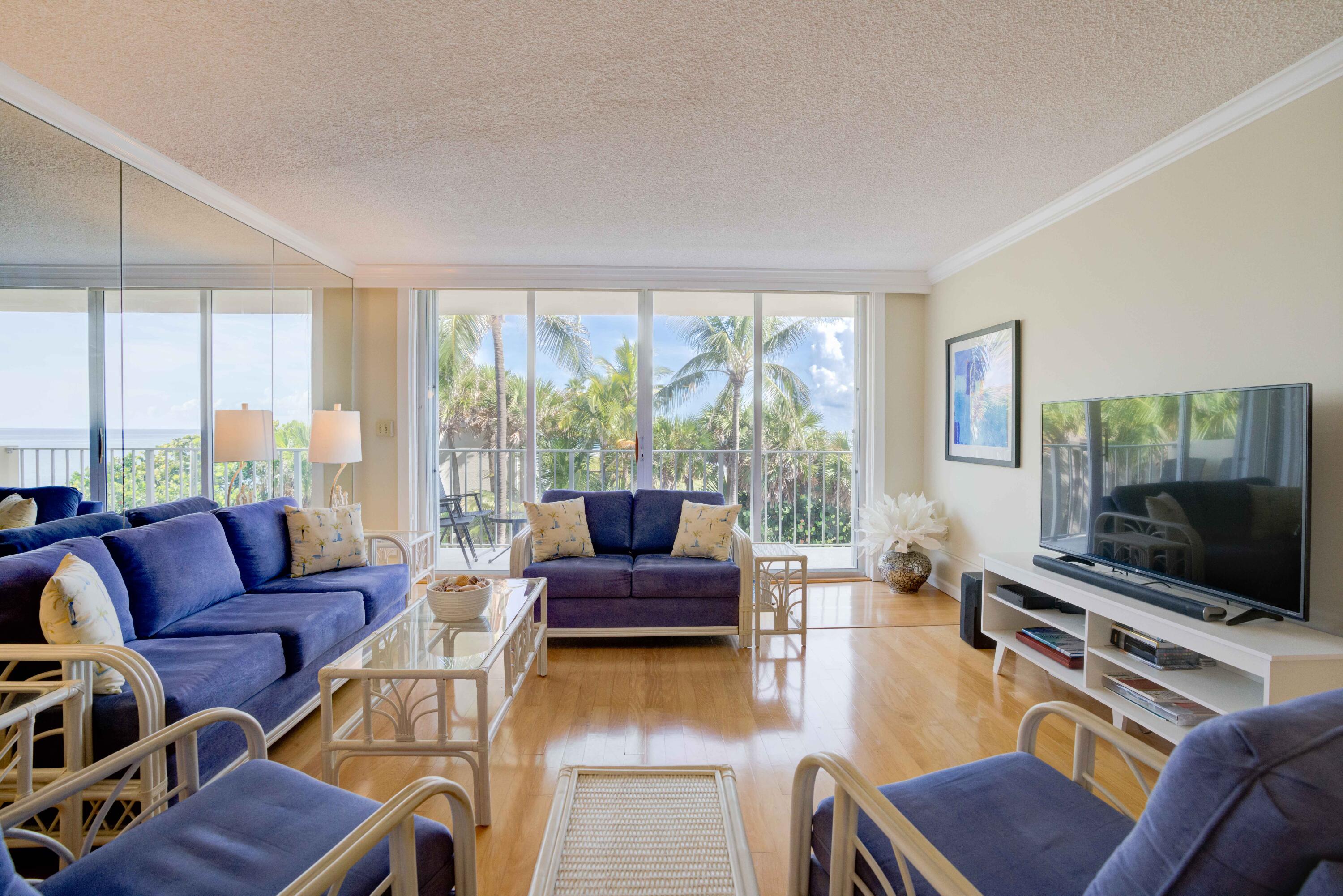 630 Ocean Drive, Unit 302 Juno Beach, FL 33408 - Photo 2 of 40 a living room with furniture a flat screen tv and a large window