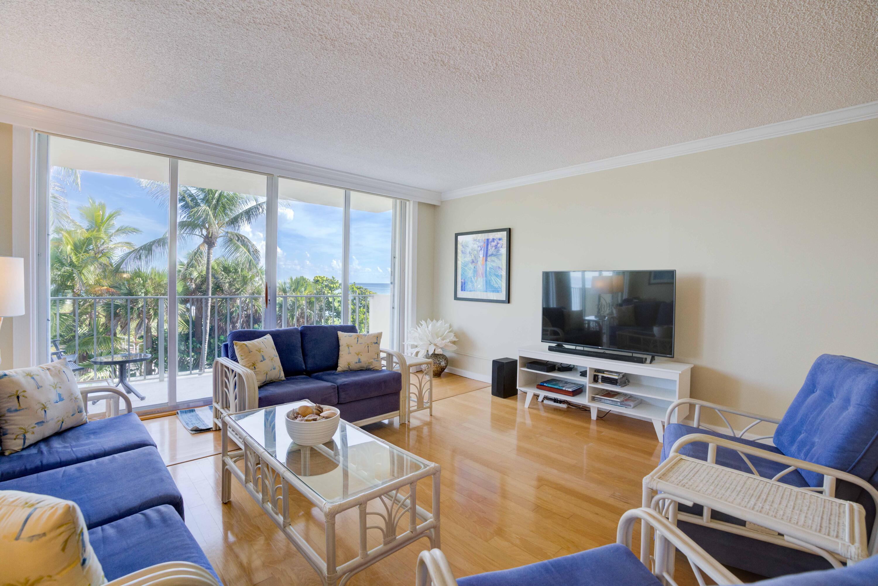 630 Ocean Drive, Unit 302 Juno Beach, FL 33408 - Photo 3 of 40 a living room with furniture a flat screen tv and a large window
