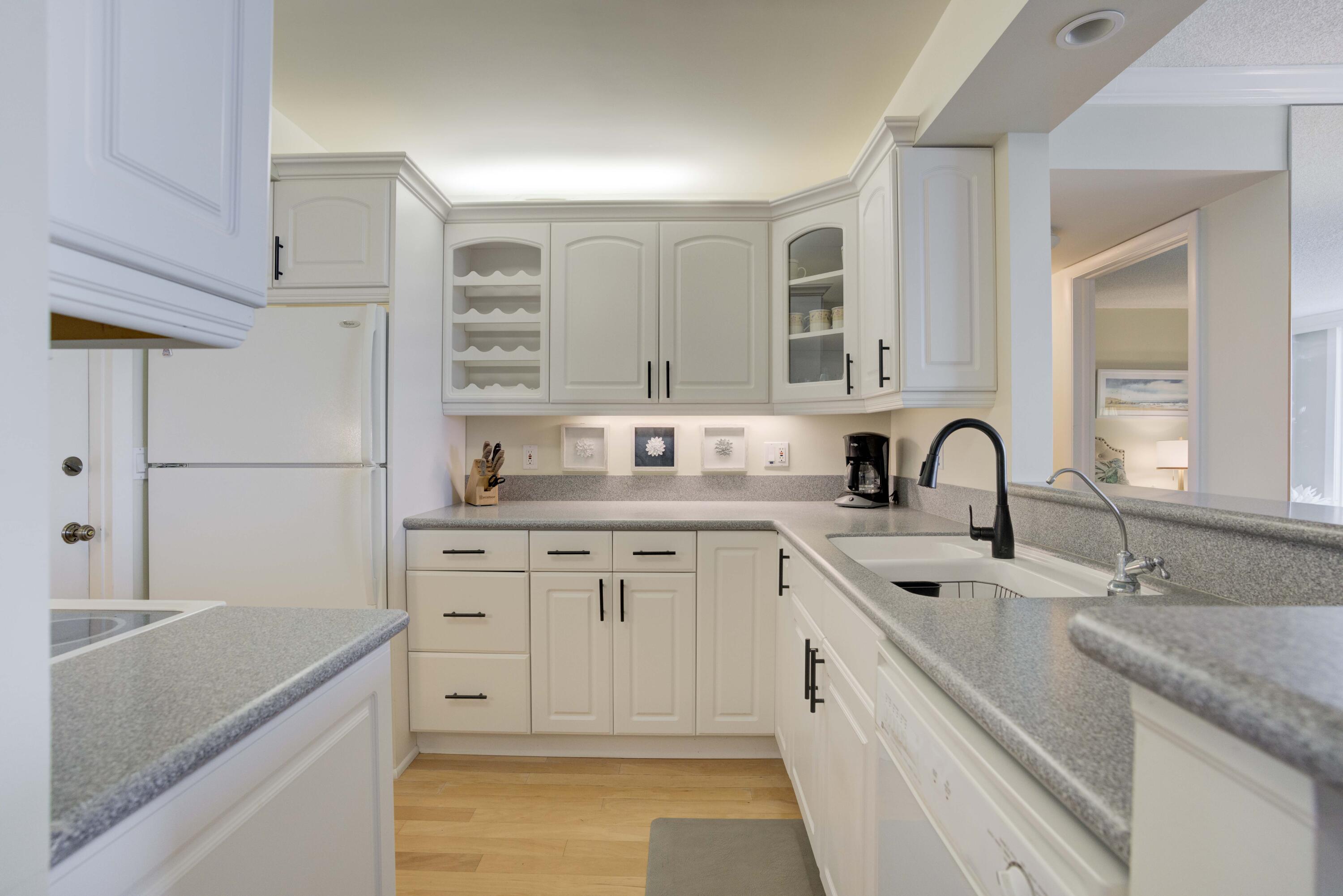 630 Ocean Drive, Unit 302 Juno Beach, FL 33408 - Photo 7 of 40 a kitchen with granite countertop a sink stainless steel appliances and cabinets