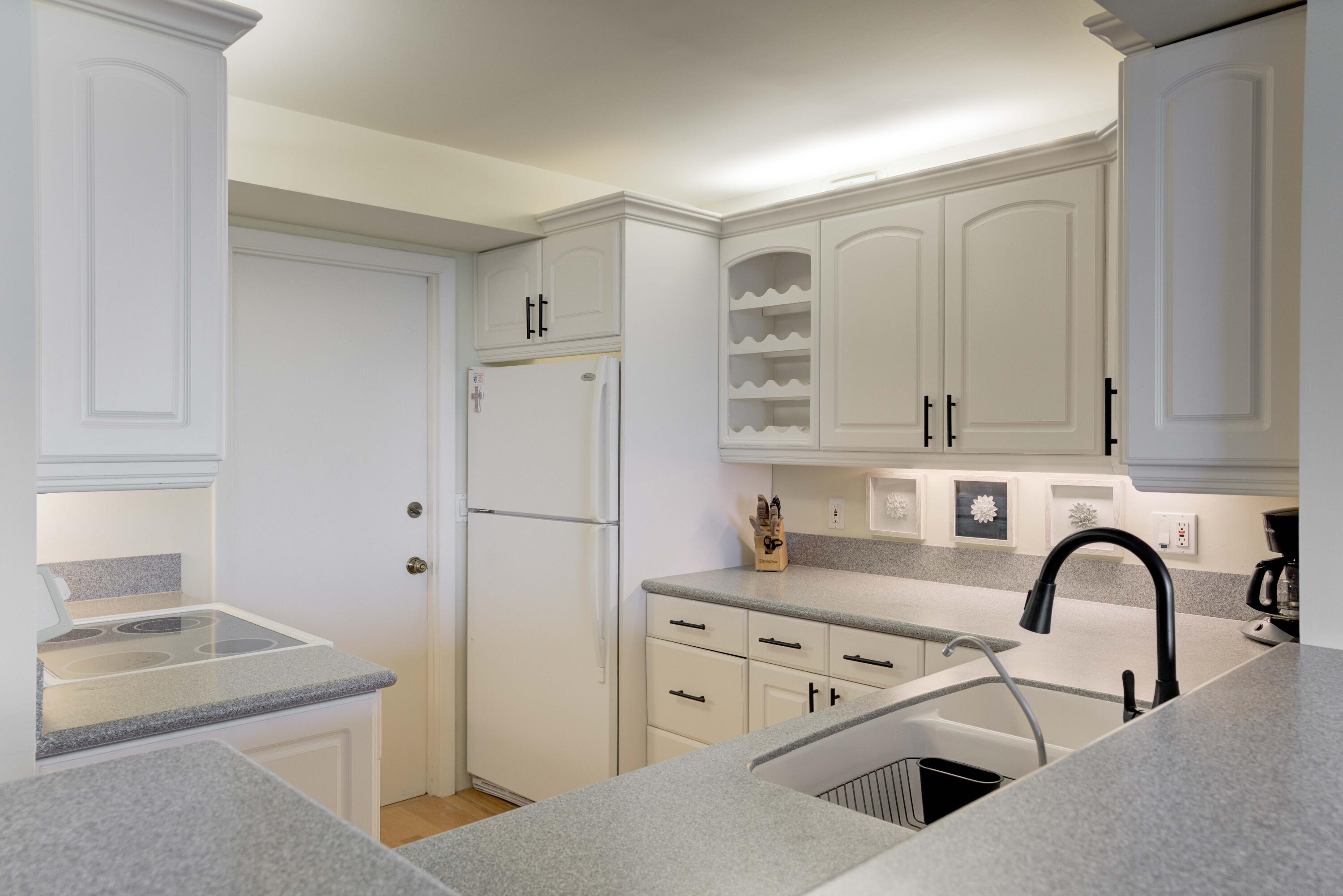 630 Ocean Drive, Unit 302 Juno Beach, FL 33408 - Photo 8 of 40 a kitchen with white cabinets and white appliances