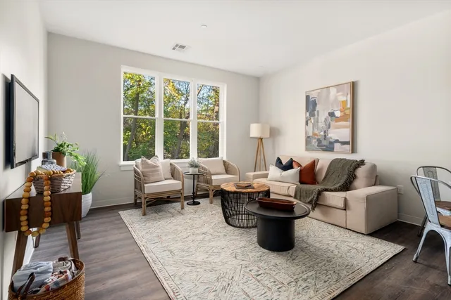 a living room with furniture large window and wooden floor