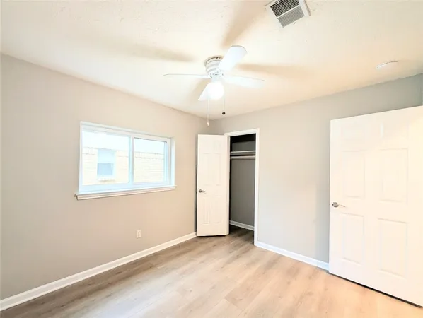 an empty room with a ceiling fan and a window
