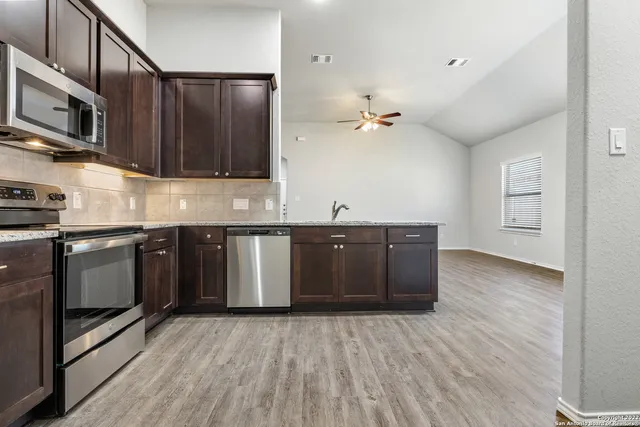 a kitchen with stainless steel appliances granite countertop a sink and wooden cabinets