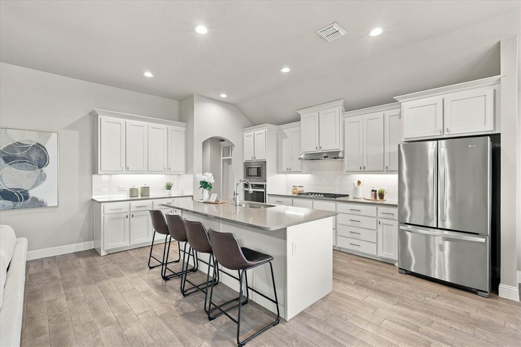 915 Timber Ridge Drive Justin, TX 76247 - Photo 9 of 34 Spacious kitchen with a central island, white cabinetry, integrated stainless-steel appliances, recessed lighting, and wood-finish flooring