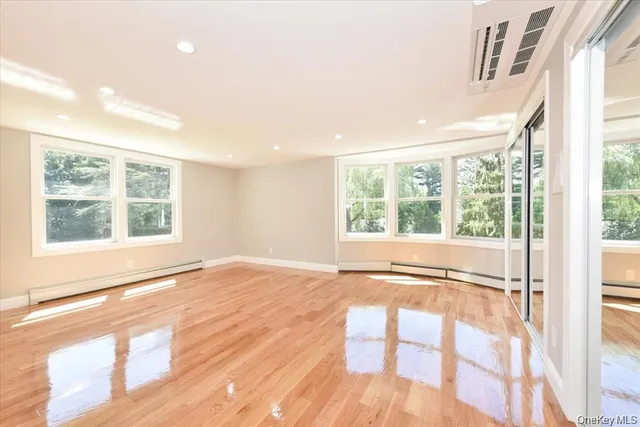 a view of an empty room with a window and wooden floor
