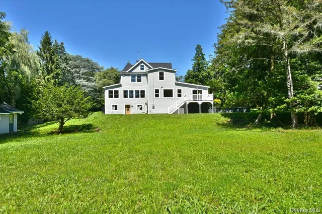a white house with a big yard and large trees