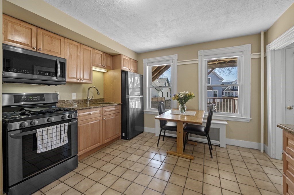 6 8 1/2 Devon Avenue, Unit 2 Beverly, MA 01915 - Photo 8 of 20 a kitchen with stainless steel appliances granite countertop a stove top oven a refrigerator a sink and chairs