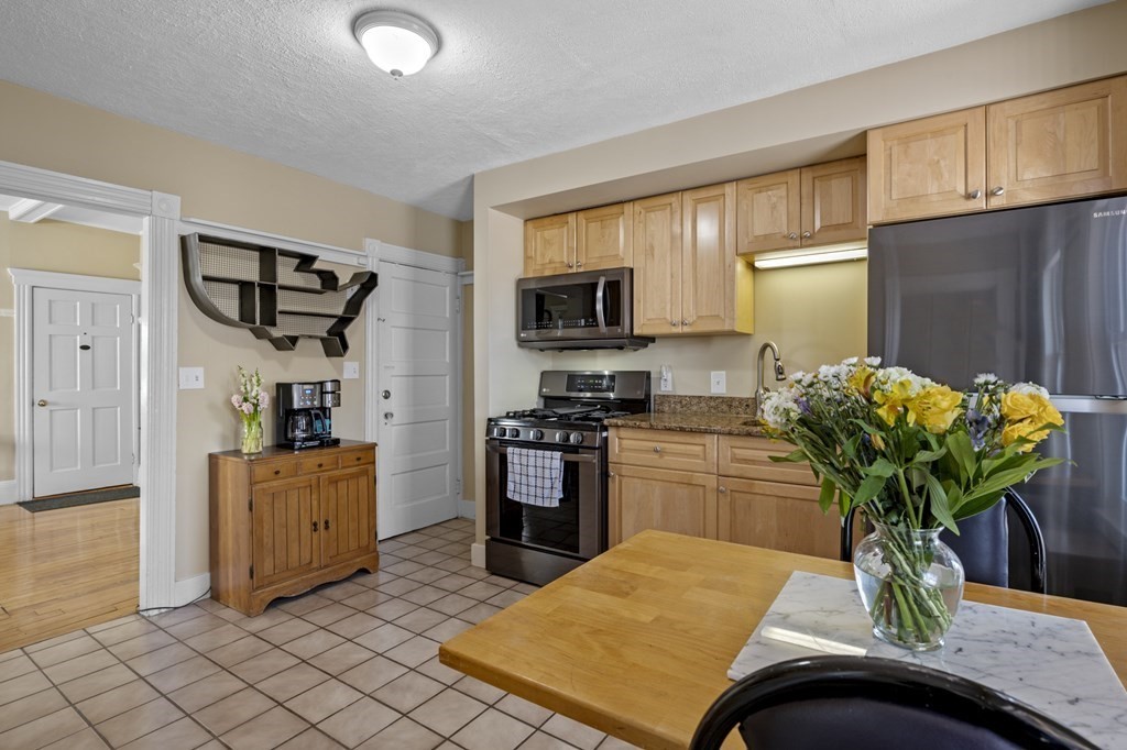 6 8 1/2 Devon Avenue, Unit 2 Beverly, MA 01915 - Photo 9 of 20 a kitchen with stainless steel appliances kitchen island granite countertop a refrigerator a stove a sink a microwave a dining table and chairs