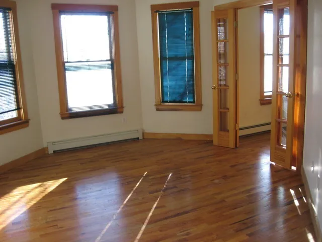 an empty room with wooden floor and windows