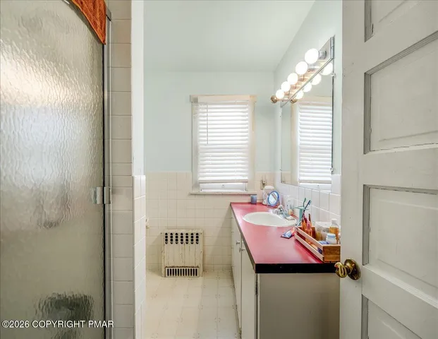 a view of a hallway with wooden floor and a bathroom