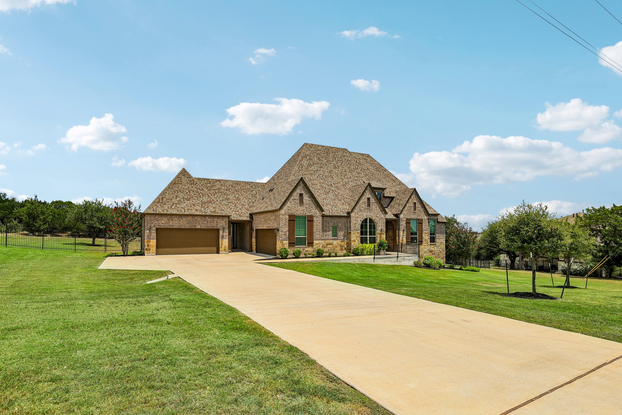 A grand brick and stone residence, featuring multiple gables and an expansive driveway, welcomes you home.