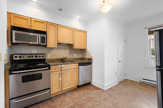a kitchen with stainless steel appliances granite countertop white cabinets and a stove top oven
