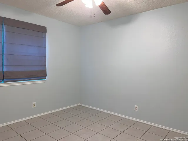 an empty room with chandelier fan