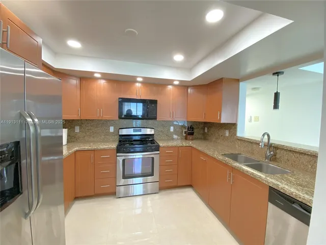 a kitchen with stainless steel appliances granite countertop a stove a sink and a refrigerator