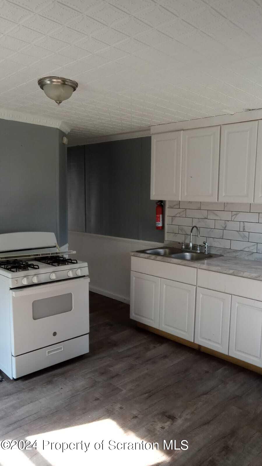 1774 Brick Avenue, Unit 1 Scranton, PA 18508 - Photo 2 of 8 a kitchen with granite countertop a stove a sink and white cabinets