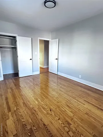 a view of an empty room with wooden floor and windows