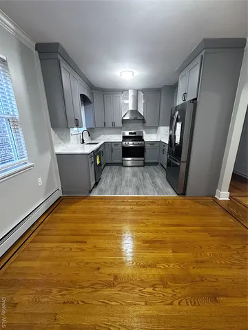 a view of kitchen and empty room with wooden floor