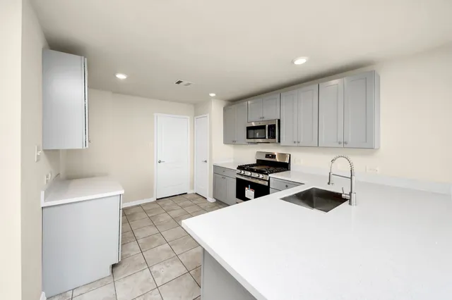 a kitchen with stainless steel appliances a sink a stove a microwave a sink a refrigerator and cabinets