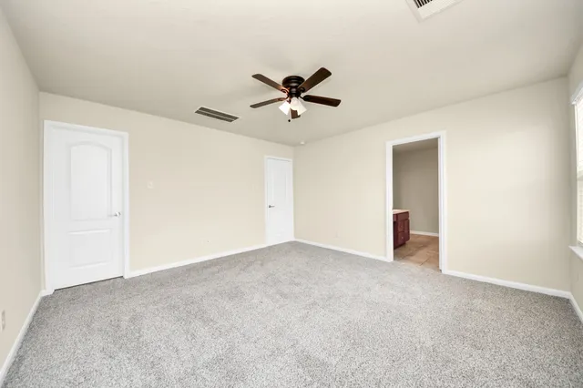 an empty room with closet and a ceiling fan