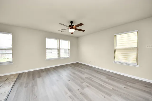 a view of an empty room with a window and a chandelier fan