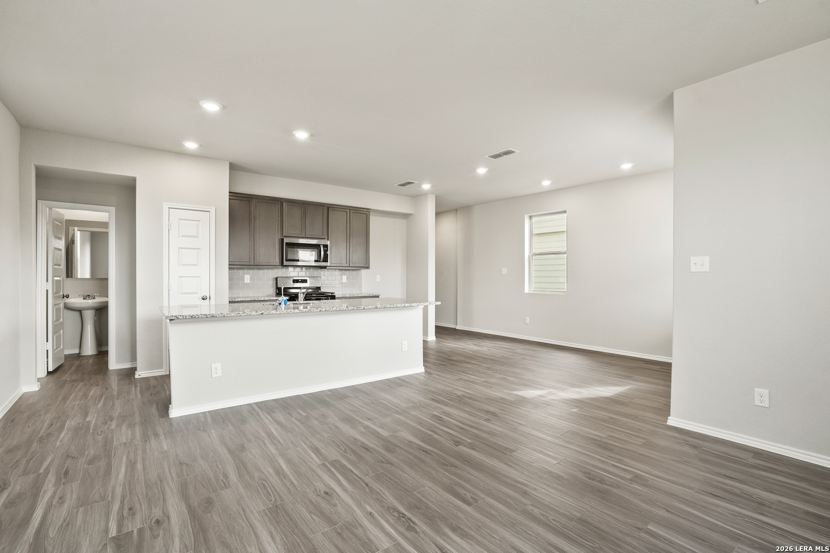 4951 Blue Ranch San Antonio, TX 78222 - Photo 6 of 36 a view of kitchen with kitchen island wooden floor granite counter tops and white stainless steel appliances