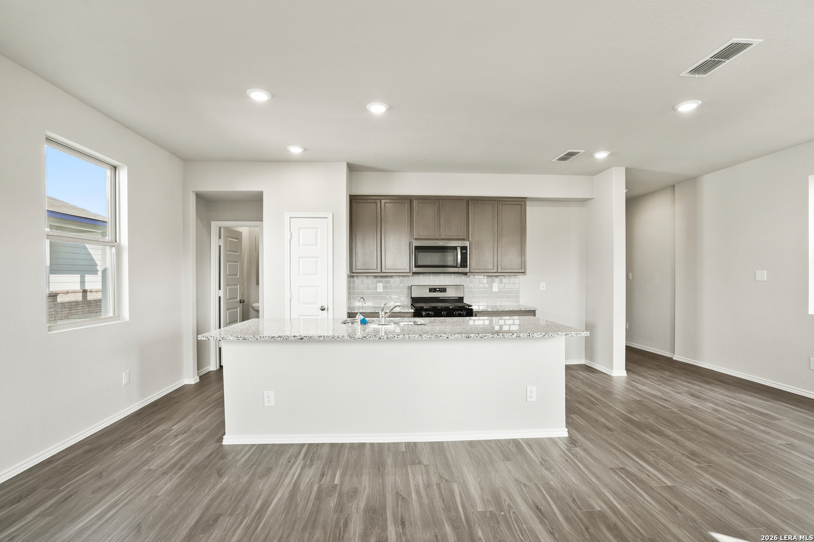 4951 Blue Ranch San Antonio, TX 78222 - Photo 8 of 36 a large white kitchen with wooden floor and stainless steel appliances