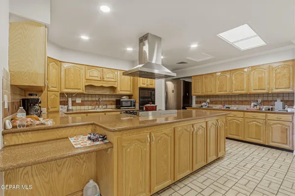 a large kitchen with stainless steel appliances a large counter top a stove and a refrigerator