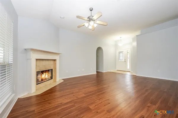 a view of an empty room with wooden floor and a ceiling fan