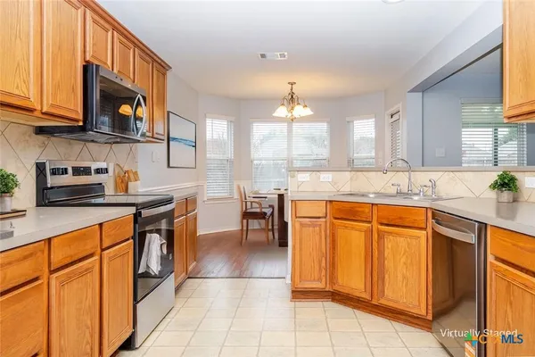 a kitchen with stainless steel appliances granite countertop a stove a sink and a microwave