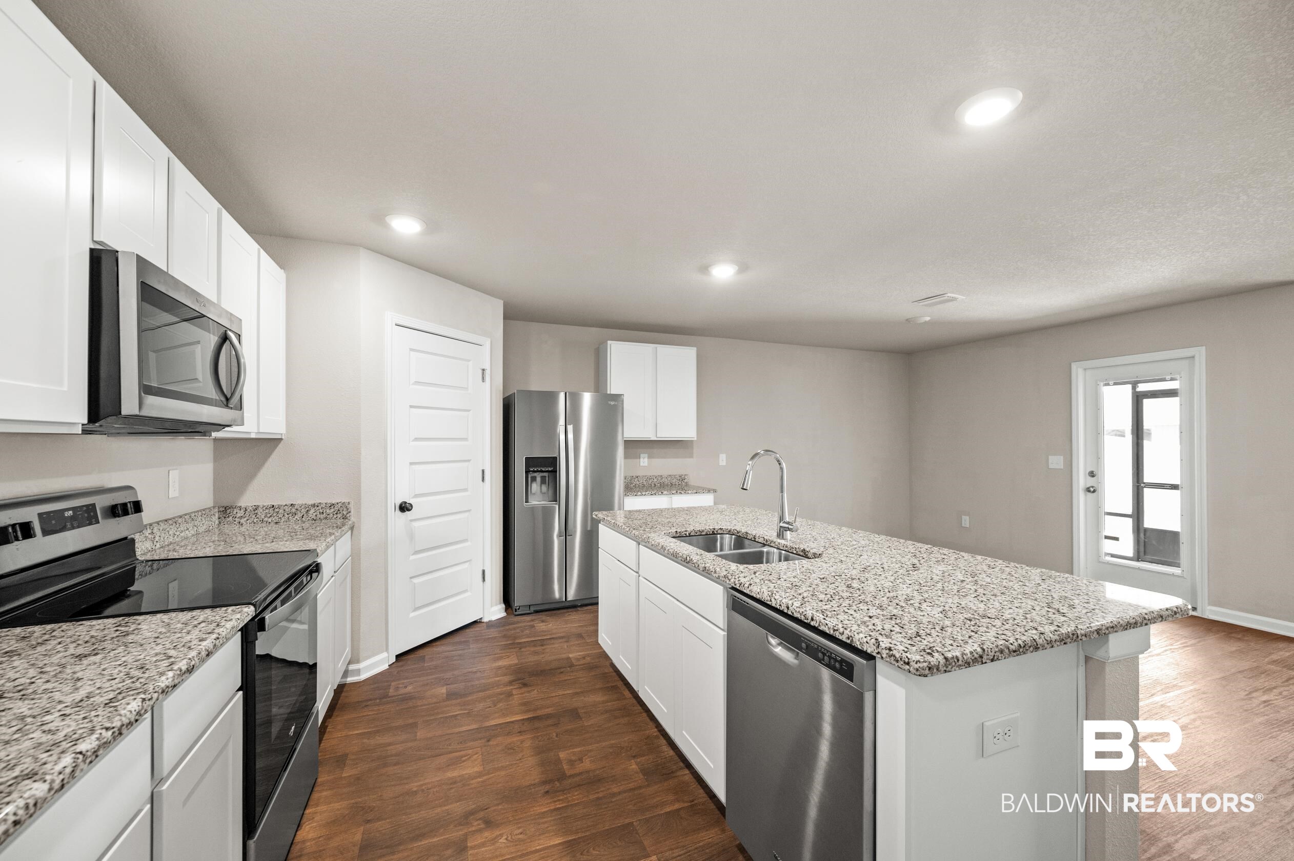 10353 Zenyatta Loop Daphne, AL 36526 - Photo 3 of 33 Kitchen with dark hardwood / wood-style flooring, appliances with stainless steel finishes, an island with sink, sink, and white cabinetry