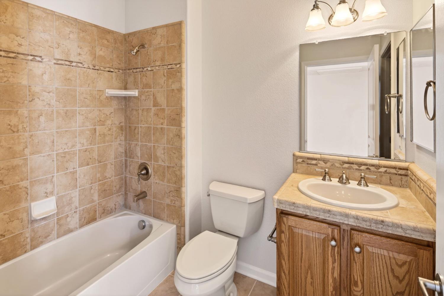 1260 Freschi Lane Lincoln, CA 95648 - Photo 39 of 60 a bathroom with a granite countertop sink a toilet a mirror a bathtub and shower