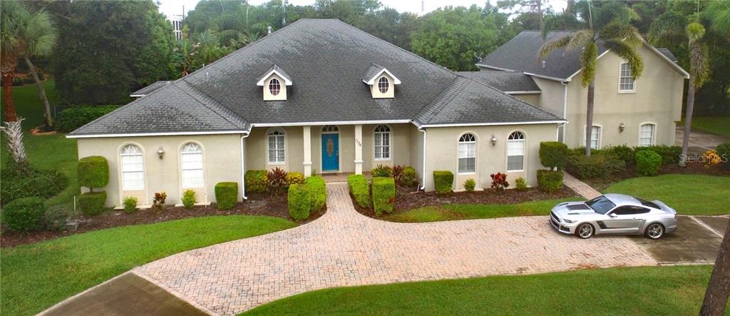 1136 Candler Road Clearwater, FL 33765 - Photo 1 of 1 Front view of 1136 Candler showing the main house and 4 car garage with addition above it on the right. Pavered section of the circular drive is right in front. Entrance to in-law/guest area - you can see the walkway to that door right behind the Mustang. Note: this photo was taken right after a rain so drive and roof are wet here.
