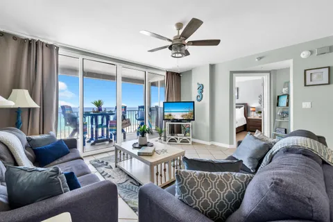 a living room with furniture a ceiling fan and a large window