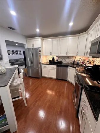 a kitchen with a sink a stove a refrigerator and wooden floor