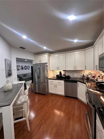 a kitchen with stainless steel appliances kitchen island granite countertop a table chairs stove and refrigerator