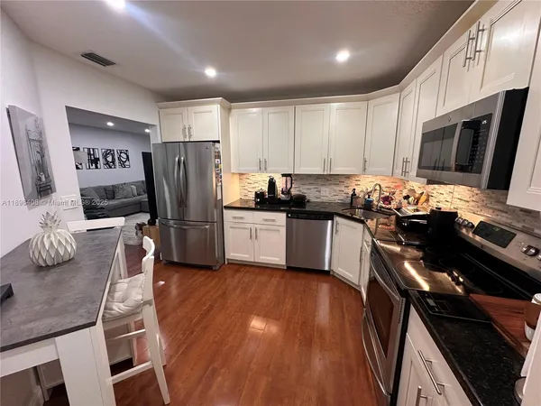 a kitchen with stainless steel appliances granite countertop a refrigerator stove microwave and sink