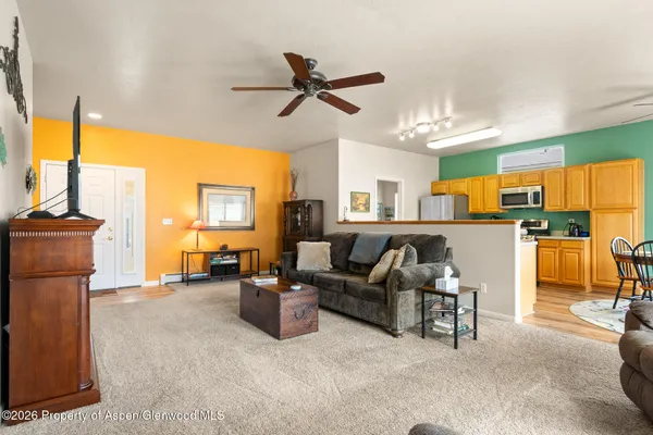 a living room with couches a flat screen tv and kitchen view