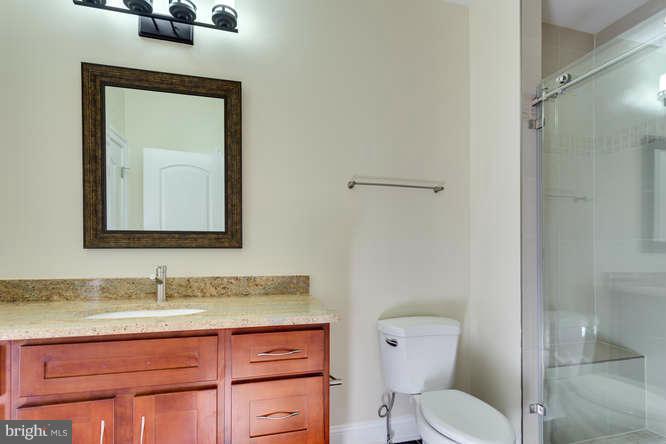 9423 Old Courthouse Road Vienna, VA 22182 - Photo 24 of 30 a bathroom with a granite countertop toilet sink and mirror