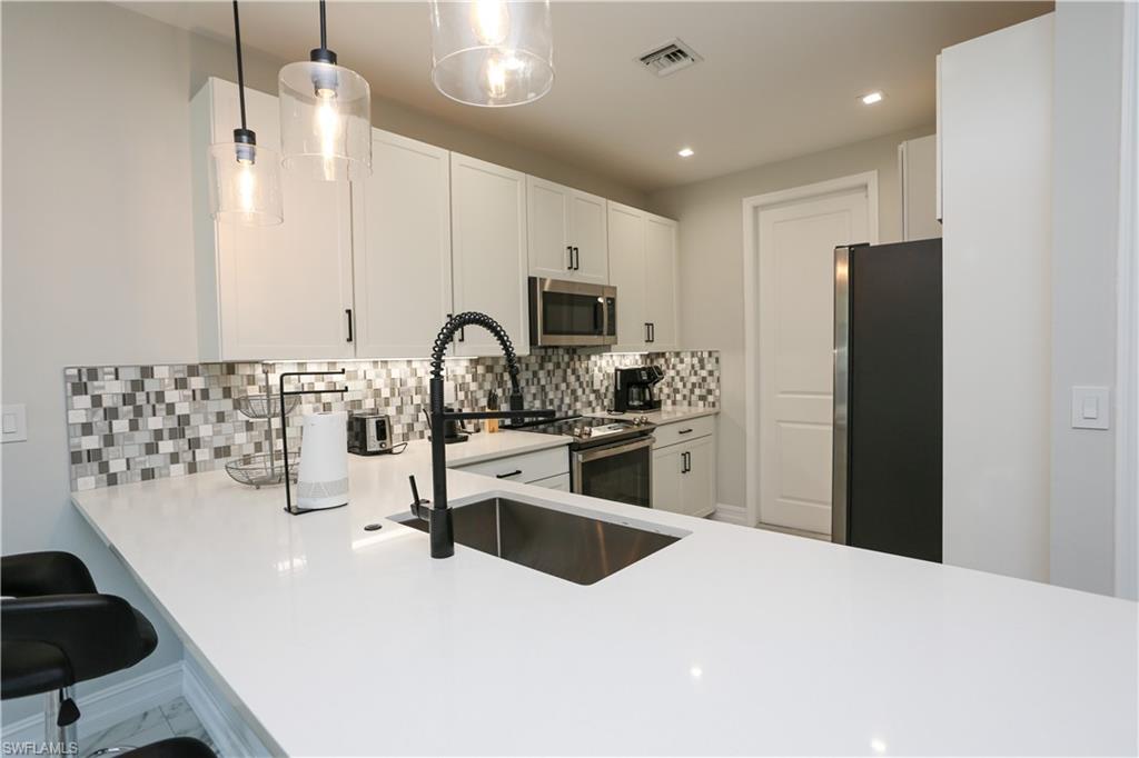7654 Rockefeller Drive Naples, FL 34119 - Photo 12 of 35 a kitchen with stainless steel appliances a sink stove and refrigerator