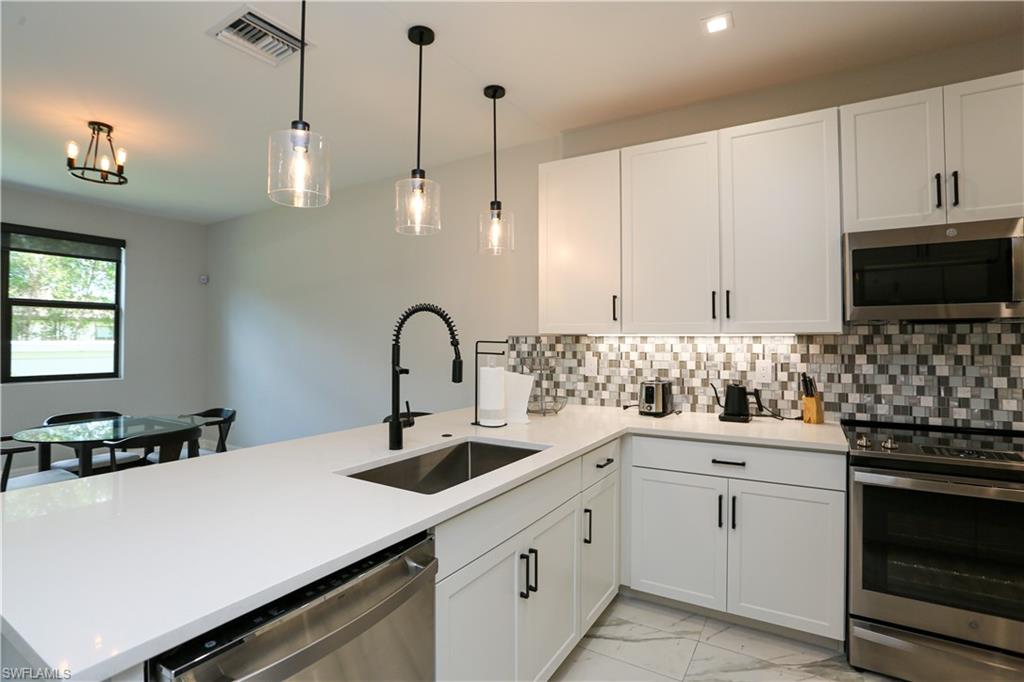 7654 Rockefeller Drive Naples, FL 34119 - Photo 16 of 35 a kitchen with sink a microwave and cabinets